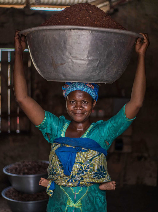 Ghanese vrouw draagt grote schaal met sheanoten op hoofd