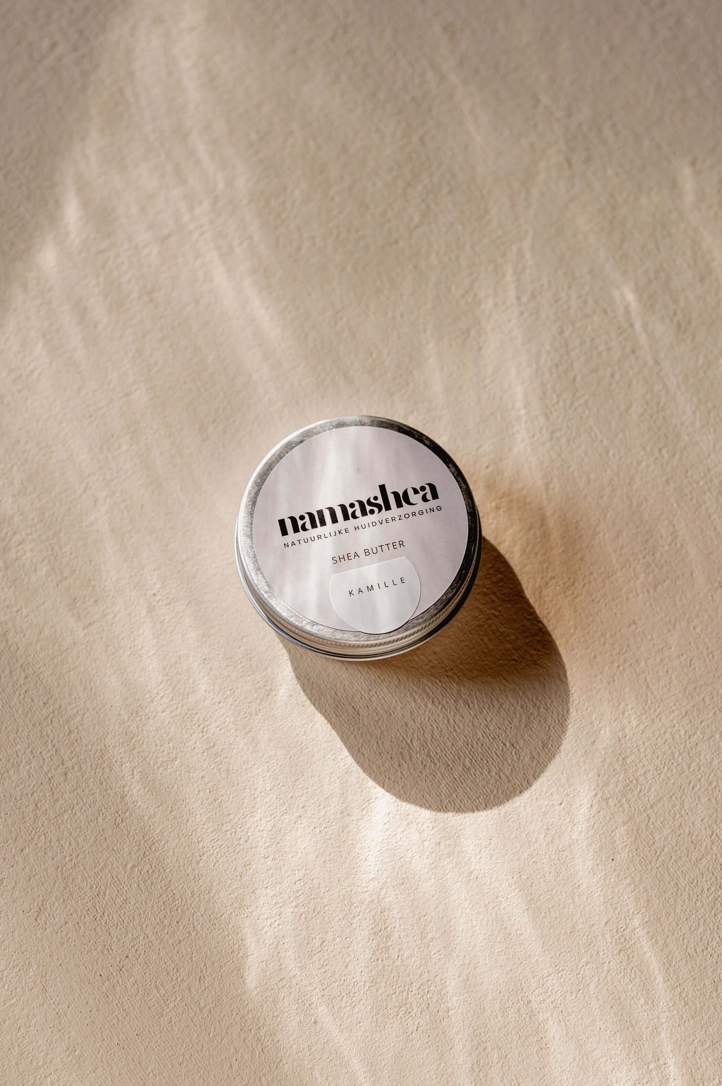 Namashea shea butter 60 ml jar with chamomile oil, displayed on a textured surface, emphasizing natural skincare.