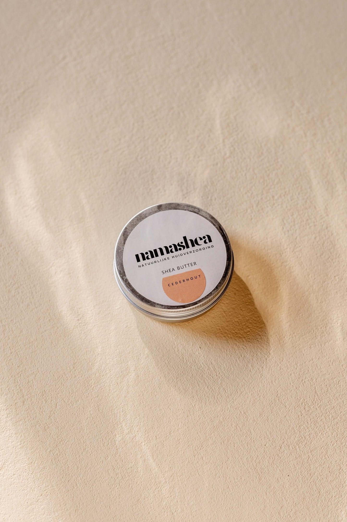 Nanashea shea butter cream in a tin on a textured surface, highlighting its natural skincare benefits.