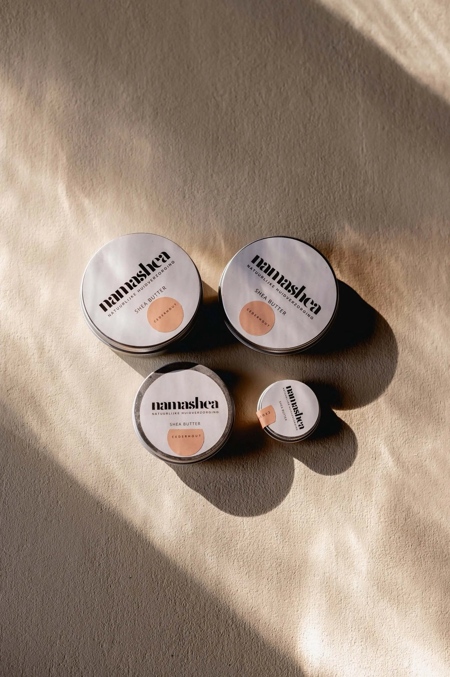 Natuurlijke shea butter producten in verschillende maten op een lichte achtergrond, perfect voor huidverzorging.