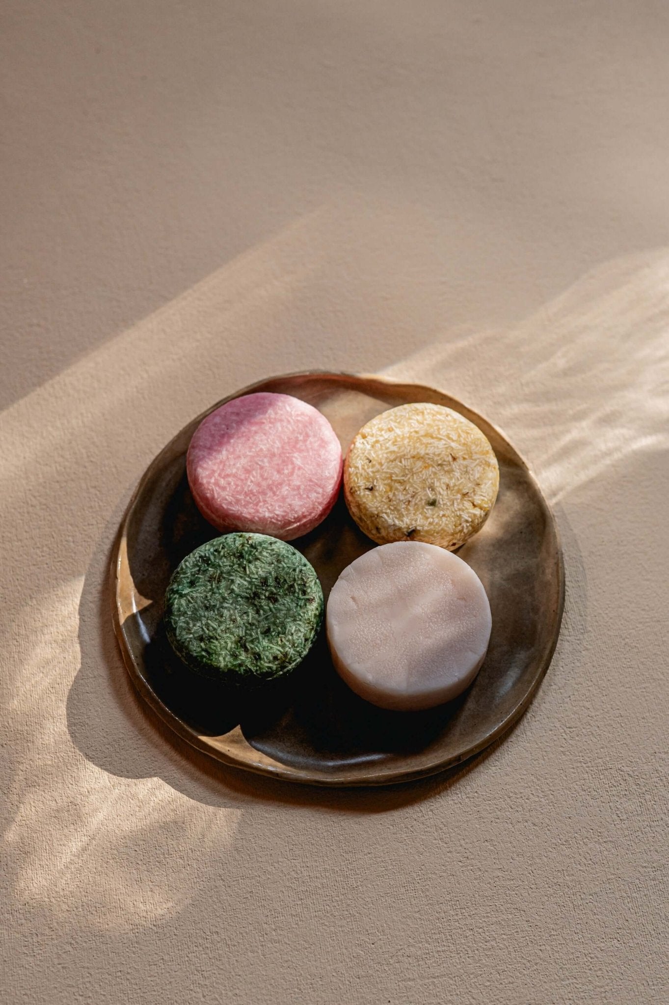 4 shampoo bars bovenaanzicht op bord op beige achtergrond