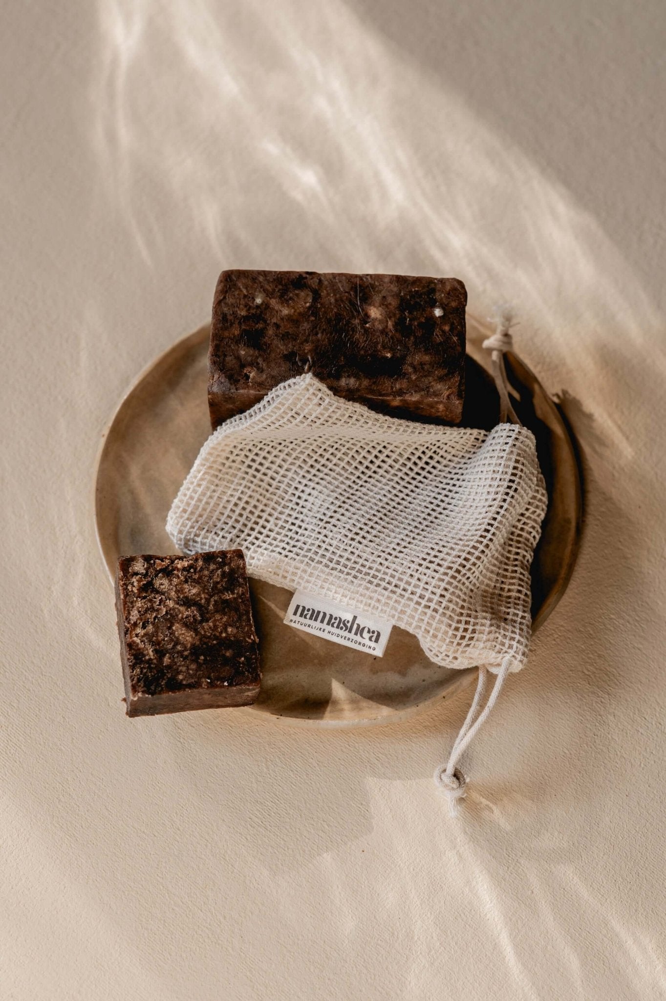 Namashea African Black Soap in katoenen zeepnetje, sfeervolle close-up in badkamerstijl