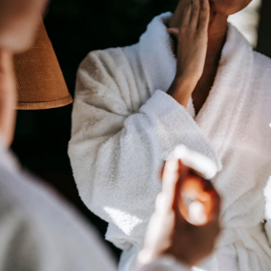 vrouw in badjas smeert creme op gezicht 