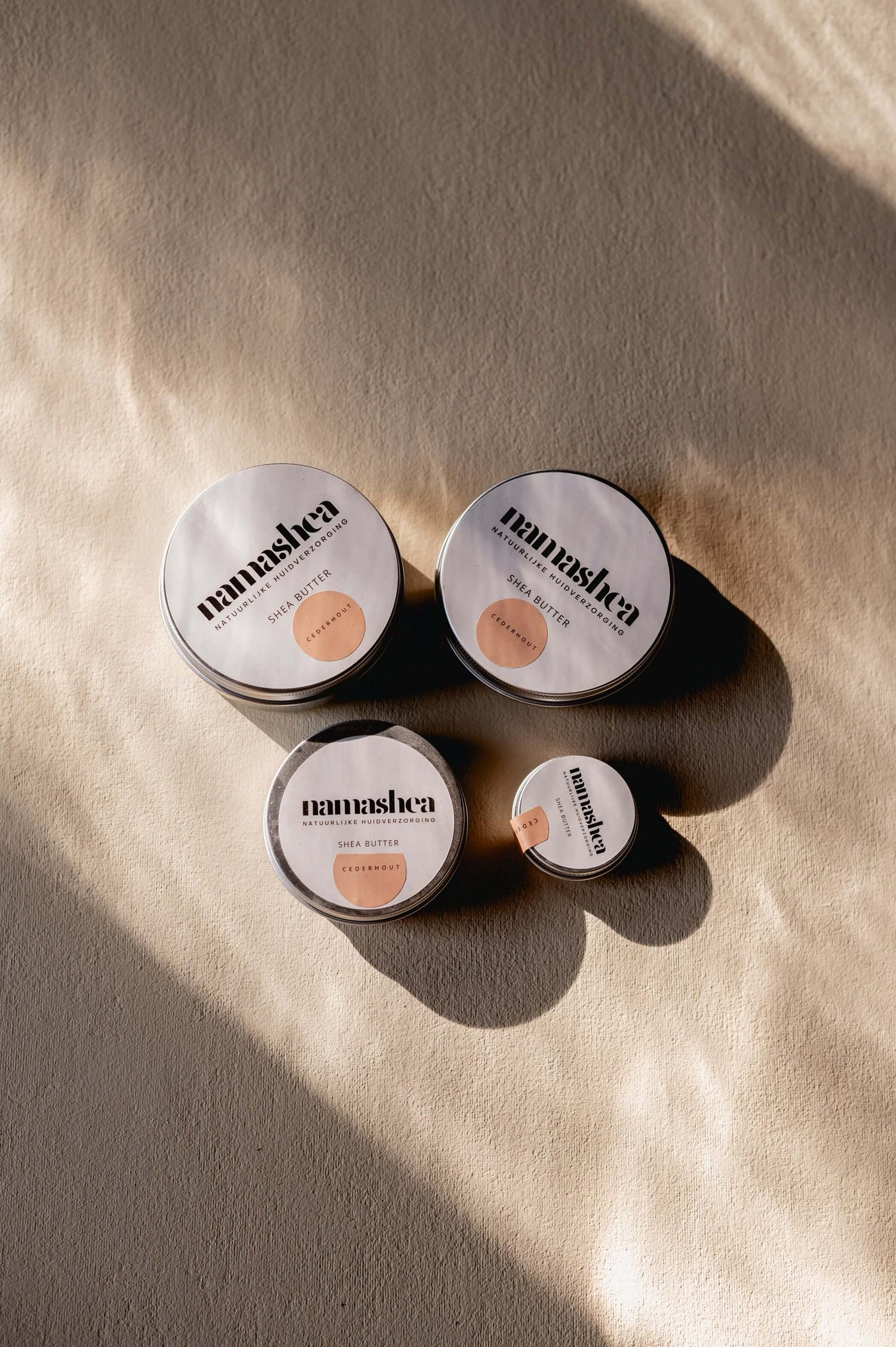 Natuurlijke shea butter producten in verschillende maten op een lichte achtergrond, perfect voor huidverzorging.