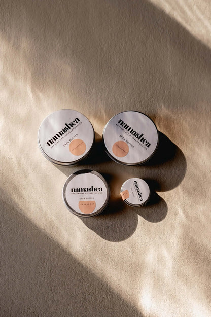 Natuurlijke shea butter producten in verschillende maten op een lichte achtergrond, perfect voor huidverzorging.
