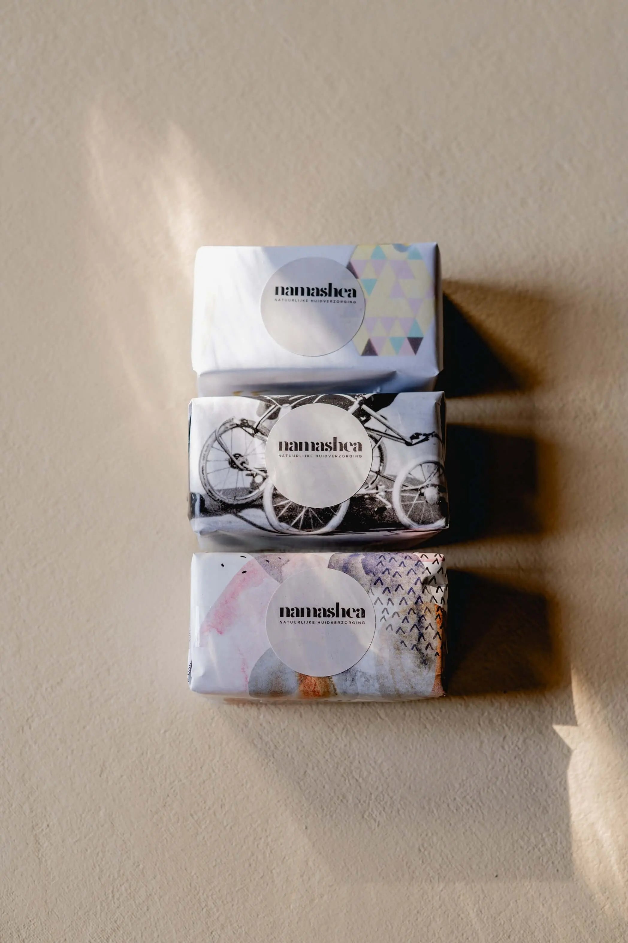 Namashea African Black Soap 200 gram, bovenaanzicht van drie ingepakte blokken met Namashea-sticker op een beige ondergrond.