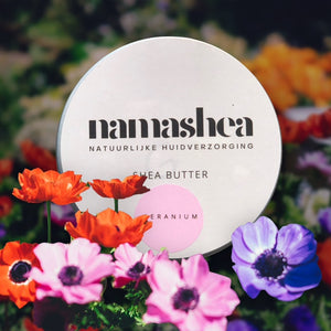 blik shea boter met geraniumolie met gekleurde bloemen op de voorgrond