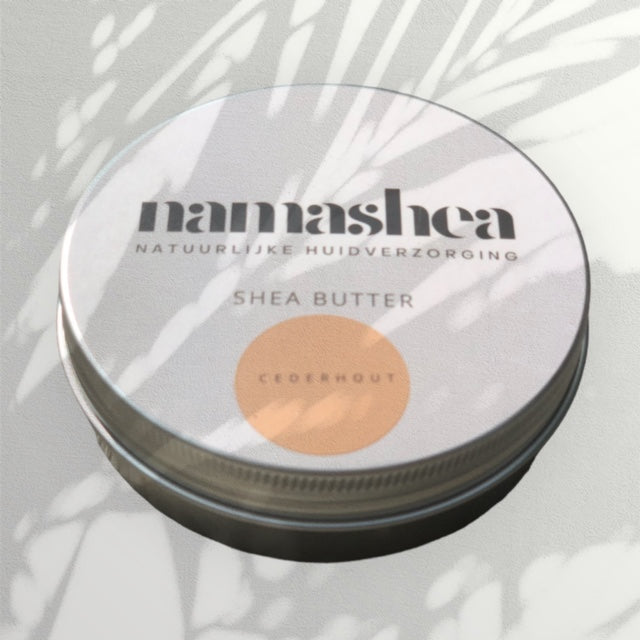blik shea boter van Namashea met cederhoutolie op grijze achtergrond met schaduw van palmblad